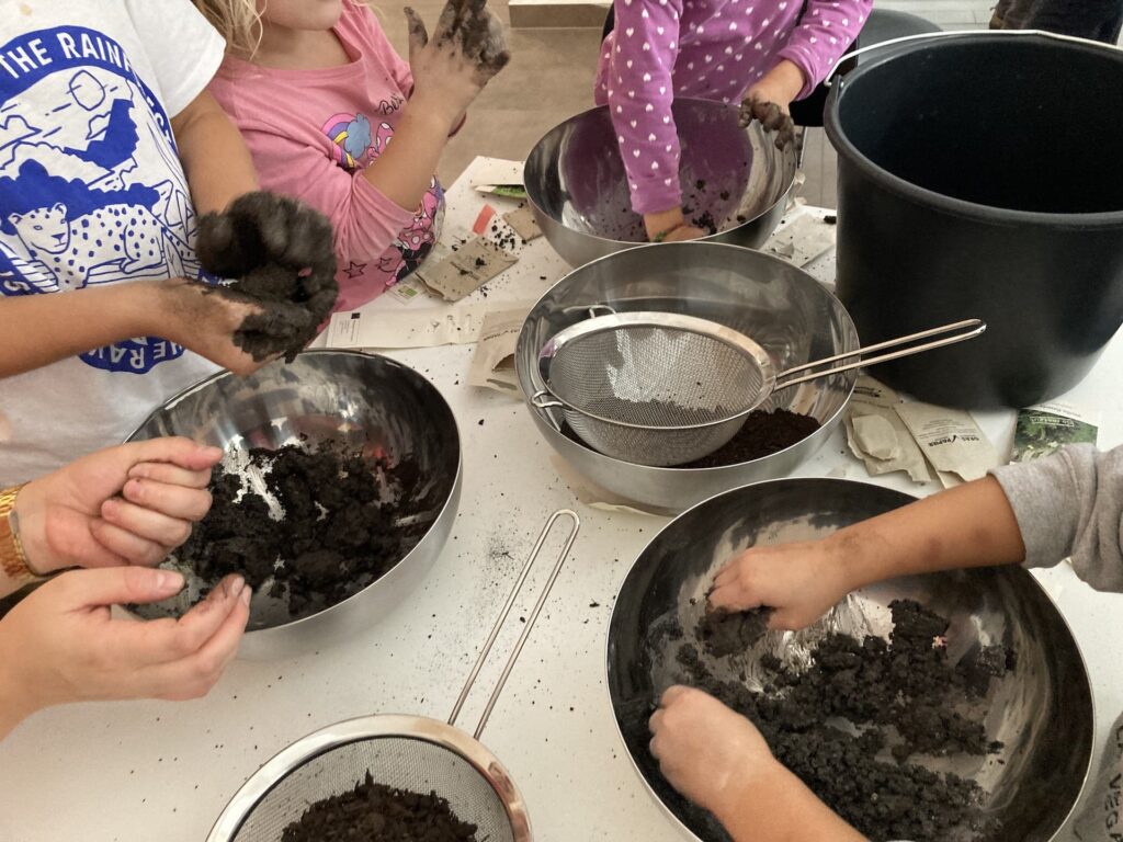Während der Workshopreihe dream.lab (2023) arbeiteten die Kinder mit Rivane Neuenschwander zum Thema Träume. Wie hier auf dem Bild zu sehen, formten sie unter anderem selbst Seed-Bombs. Seed-Bombs sind Kugeln aus natürlichen Materialien, die verschiedene Samen beinhalten. Lässt man sie in der Natur fallen, wachsen Pflanzen an ihrer Stelle. © Mona Jas