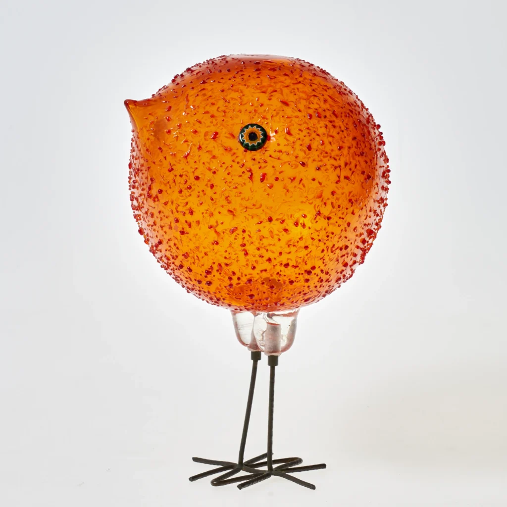Alessandro Pianon, Orangefarbenes Küken (pulcino), Murano, ca. 1960–1962 (Entwurf), Orangefarbenes Glas, frei geblasen, aufgeschmolzene rote Krösel und Mosaikglasscheiben (murrine); Kupferdraht, gehämmert, in farbloses Glas gefasst. Foto: Kunstpalast, Düsseldorf