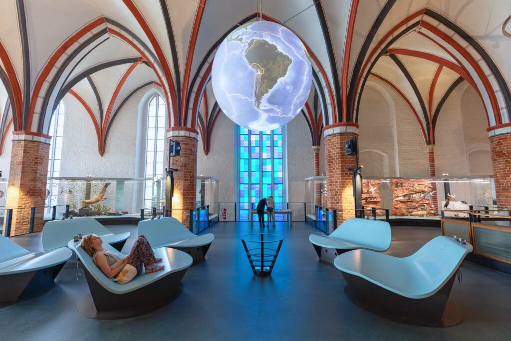 Ein digital bespielter Globus unter dem mittelalterlichen Kirchengewölbe zeigt meereskundliche Themen, Foto: Anke Neumeister/Deutsches Meeresmuseum